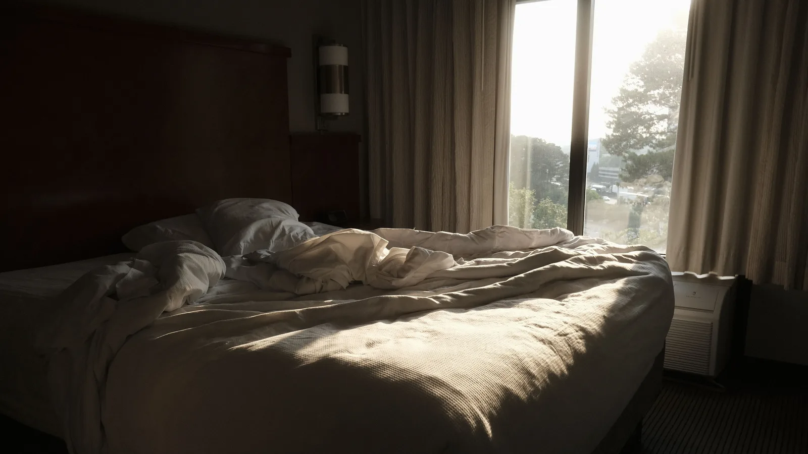 Matelas d'un lit double dont un côté est plus enfoncé que l'autre, draps défaits au petit matin.